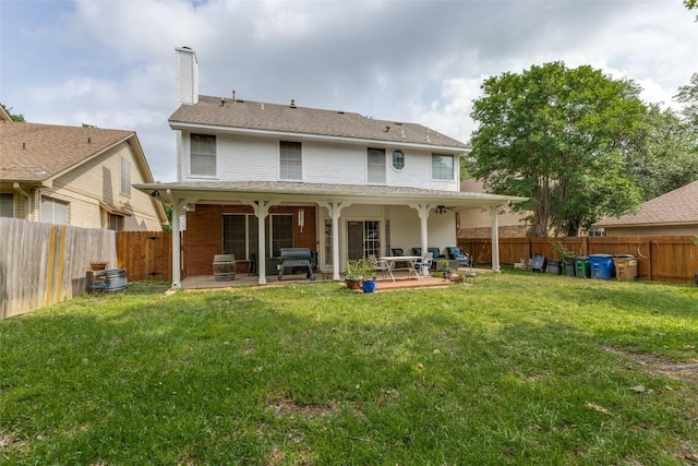 back of house featuring a fenced backyard, a patio area, a yard, and a chimney