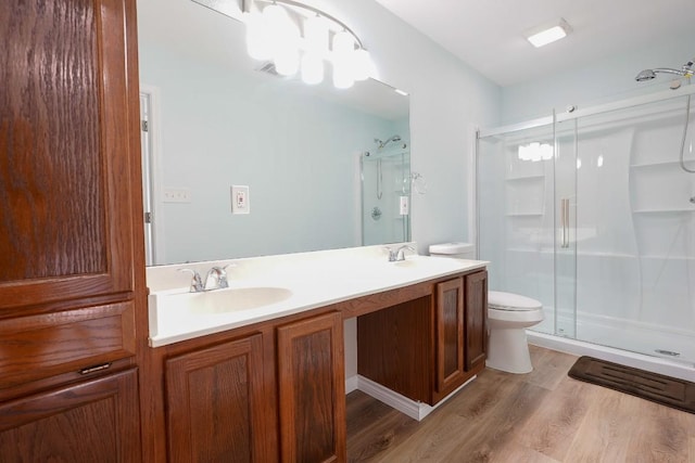 full bathroom featuring double vanity, wood finished floors, toilet, a shower stall, and a sink