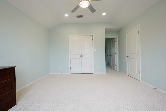 unfurnished bedroom featuring visible vents, lofted ceiling, a closet, and light colored carpet