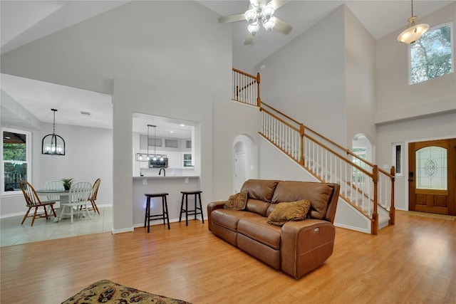 103 Sierra Ridge Dr, San Marcos, TX 78666 - living room featuring high vaulted ceiling, ceiling fan with notable chandelier, stairway, and light wood-style floors