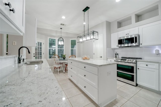 103 Sierra Ridge Dr, San Marcos, TX 78666 - kitchen featuring a sink, backsplash, light tile patterned floors, a kitchen island, and appliances with stainless steel finishes
