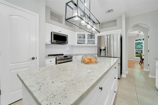 103 Sierra Ridge Dr, San Marcos, TX 78666 - kitchen with a kitchen island, visible vents, arched walkways, glass insert cabinets, and stainless steel appliances