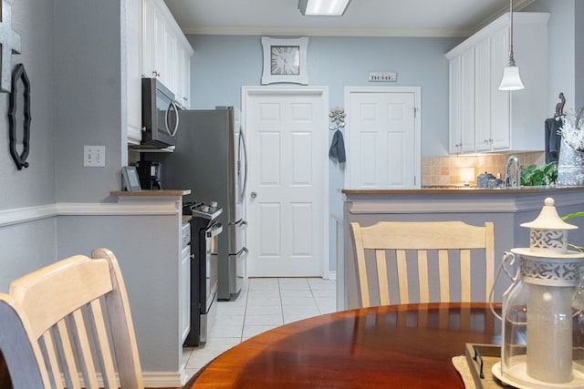kitchen featuring white cabinets, stainless steel microwave, decorative backsplash, and light tile patterned floors