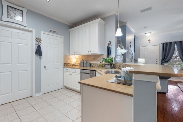 kitchen featuring a peninsula, ornamental molding, a sink, and white cabinetry
