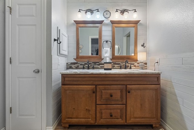 bathroom featuring double vanity, a sink, and wood walls