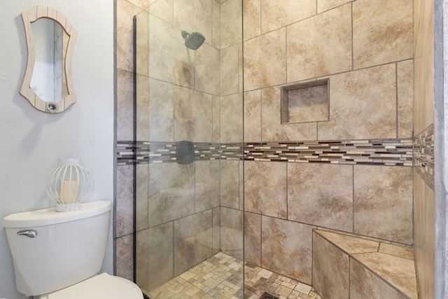bathroom featuring toilet and a shower stall