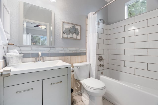 full bathroom featuring a ceiling fan, vanity, toilet, shower / tub combo with curtain, and a textured wall