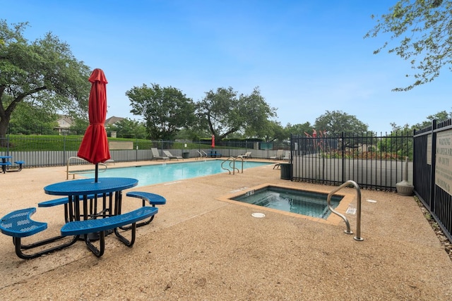 pool featuring a community hot tub, a patio area, and fence