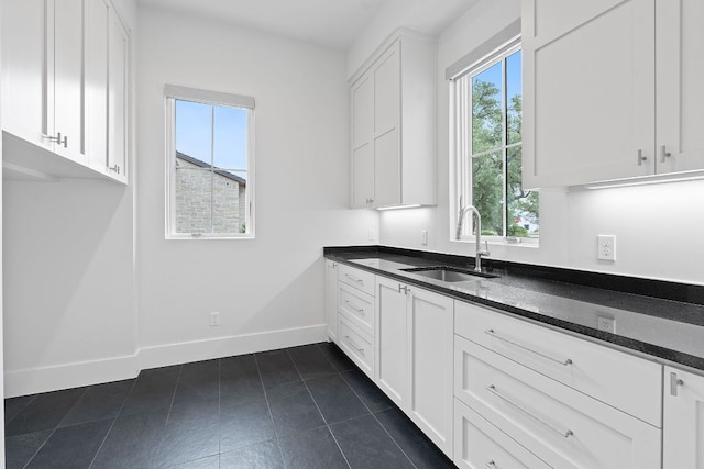 229 Tiffanie Way, Austin, TX 78737 - kitchen with white cabinetry, baseboards, a sink, and dark stone countertops