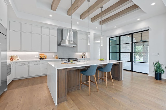 229 Tiffanie Way, Austin, TX 78737 - kitchen with a kitchen island with sink, beamed ceiling, wall chimney range hood, tasteful backsplash, and a sink