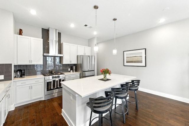 kitchen featuring visible vents, wall chimney range hood, a center island, tasteful backsplash, and stainless steel appliances