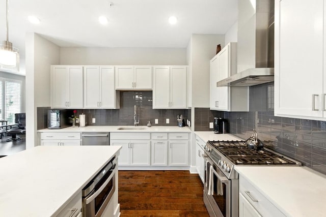 kitchen featuring white cabinetry, appliances with stainless steel finishes, a sink, and wall chimney exhaust hood