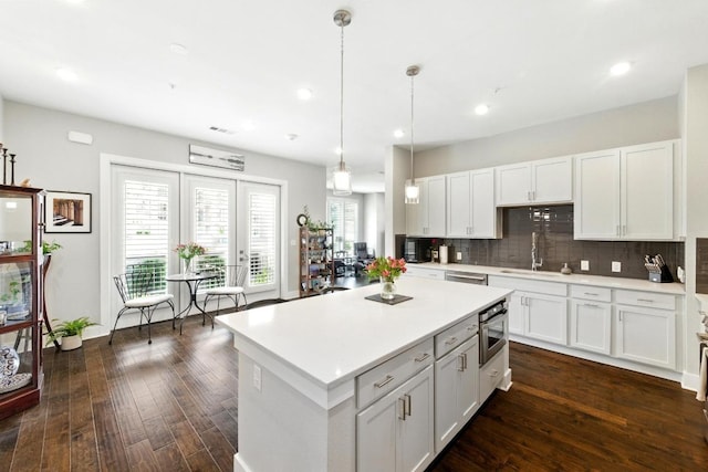 kitchen with white cabinets, tasteful backsplash, a sink, light countertops, and dark wood-type flooring