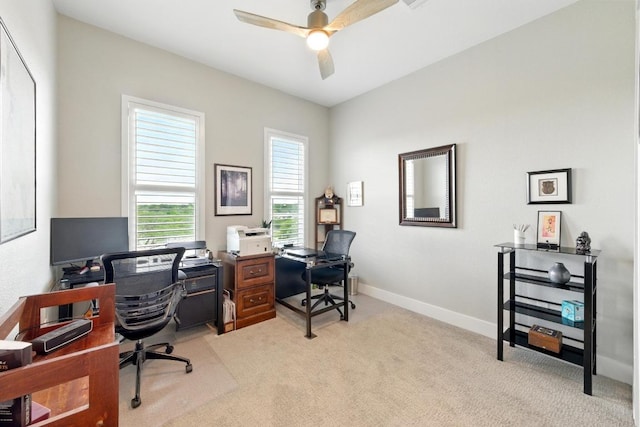office featuring baseboards, a ceiling fan, and light carpet
