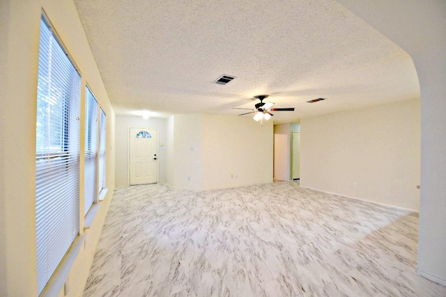 1411 Baffin Cv, Round Rock, TX 78664 - empty room featuring visible vents, a ceiling fan, a textured ceiling, and arched walkways