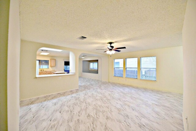 1411 Baffin Cv, Round Rock, TX 78664 - unfurnished living room featuring visible vents, arched walkways, a textured ceiling, and a ceiling fan