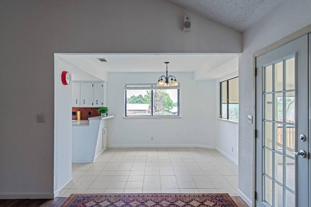 unfurnished dining area with baseboards, a notable chandelier, light tile patterned floors, and lofted ceiling
