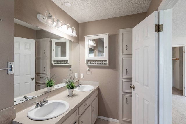 full bath with double vanity, a textured ceiling, and a sink
