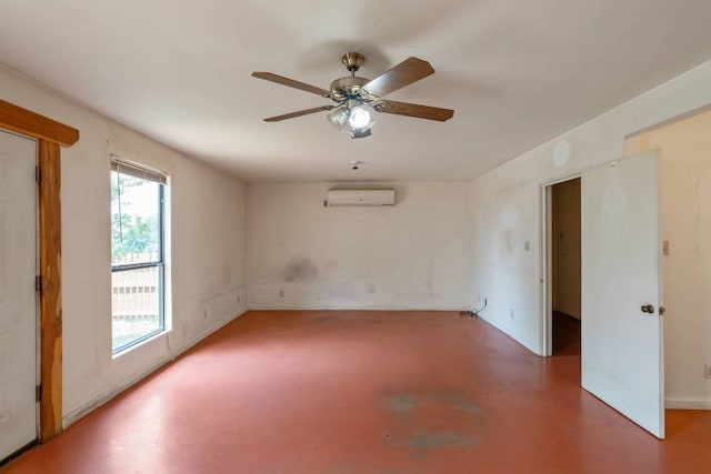 empty room with an AC wall unit, a ceiling fan, finished concrete flooring, and baseboards