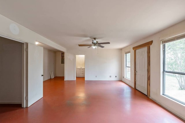 empty room with baseboards, a ceiling fan, and finished concrete flooring