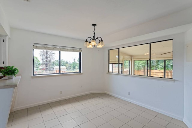 unfurnished room featuring plenty of natural light, baseboards, light tile patterned flooring, and an inviting chandelier