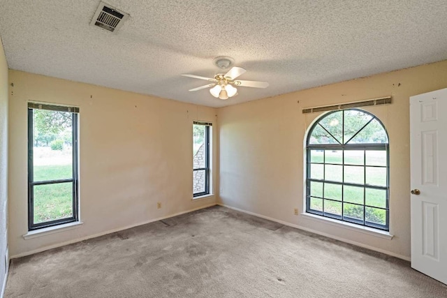 carpeted empty room with a ceiling fan, a textured ceiling, visible vents, and baseboards