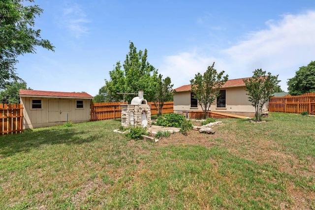 view of yard with a storage unit, a fenced backyard, and an outbuilding