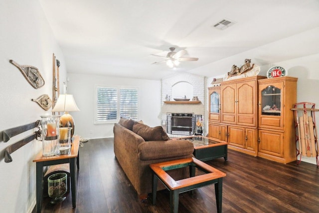 living room featuring ceiling fan, visible vents, dark wood finished floors, and a fireplace