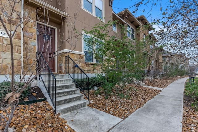 view of exterior entry featuring stucco siding and stone siding