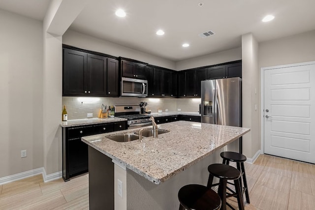 kitchen with appliances with stainless steel finishes, dark cabinetry, baseboards, and a kitchen breakfast bar