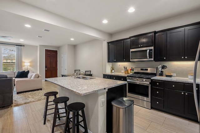 kitchen with stainless steel appliances, open floor plan, dark cabinets, and a sink
