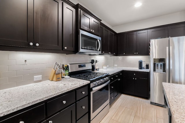 kitchen featuring appliances with stainless steel finishes, light stone counters, and tasteful backsplash