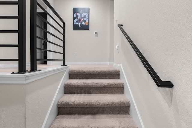 stairway featuring carpet floors and baseboards