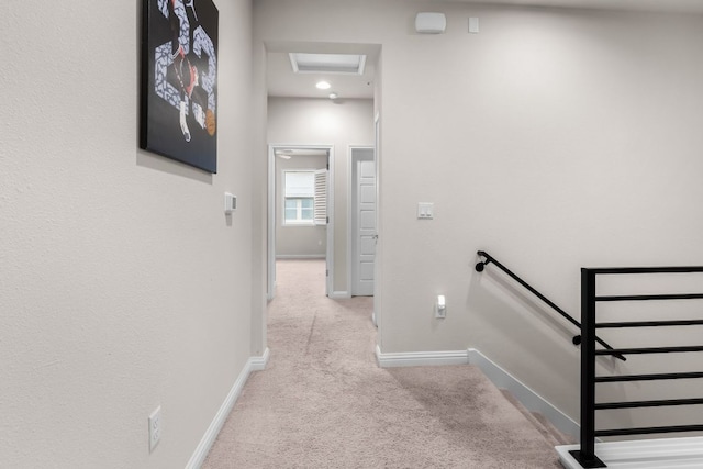hallway with baseboards, carpet flooring, attic access, and an upstairs landing