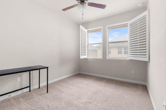 carpeted spare room featuring ceiling fan and baseboards