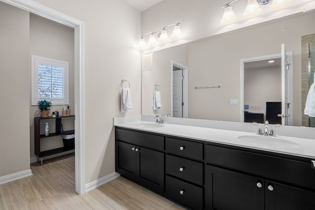 ensuite bathroom with double vanity, a sink, and wood finished floors