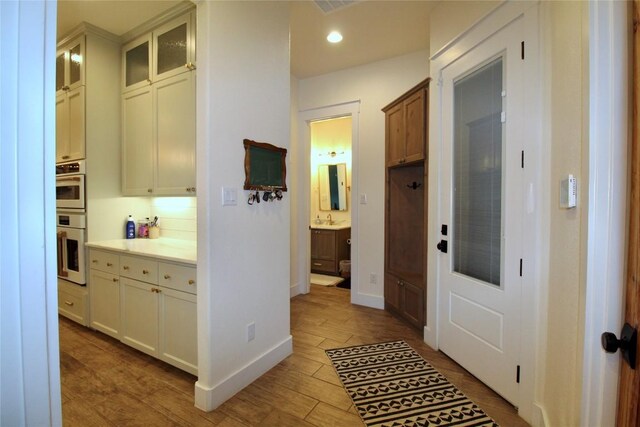 hallway featuring recessed lighting, baseboards, and wood finished floors