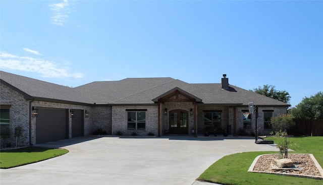 french country inspired facade with a shingled roof, brick siding, a garage, french doors, and driveway