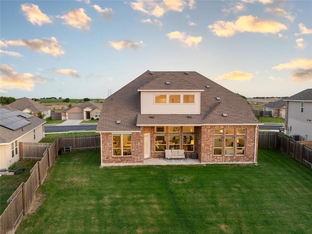 back of house featuring a yard, a patio area, and brick siding