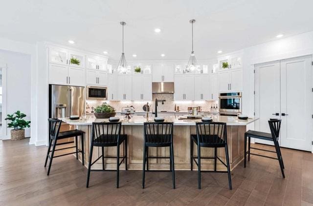 kitchen with light countertops, under cabinet range hood, a notable chandelier, and stainless steel appliances