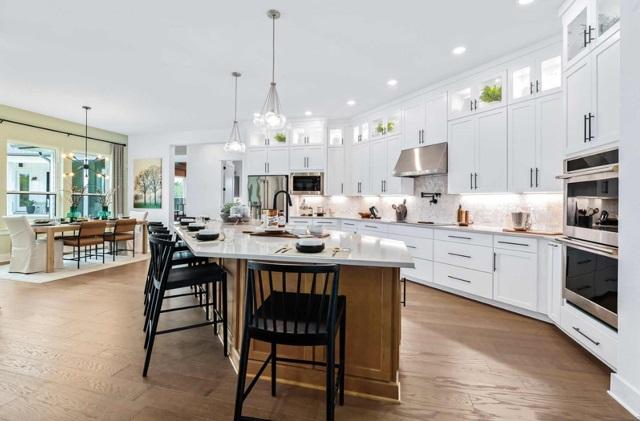 kitchen with a sink, light countertops, stainless steel appliances, backsplash, and under cabinet range hood