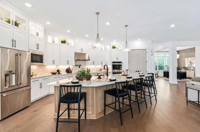 kitchen featuring wood finished floors, light countertops, appliances with stainless steel finishes, and under cabinet range hood