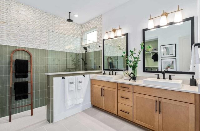 bathroom featuring a sink, tile patterned floors, a tile shower, and double vanity