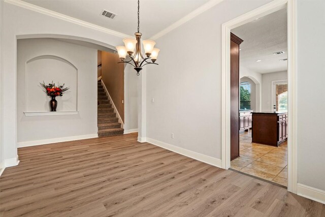 462 Shelf Rock, Driftwood, TX 78619 - spare room with arched walkways, a chandelier, light wood-type flooring, ornamental molding, and baseboards