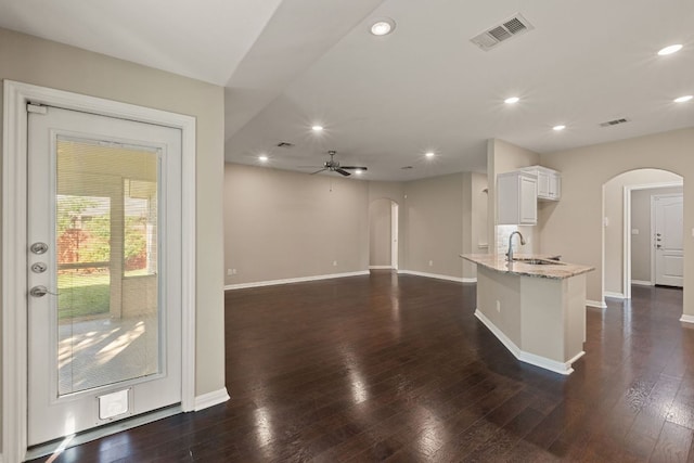 425 Valley Oaks Loop, Georgetown, TX 78626 - kitchen with arched walkways, light stone countertops, baseboards, and recessed lighting
