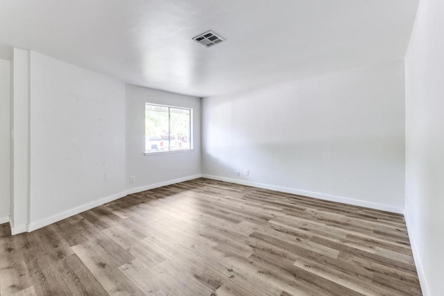 unfurnished room featuring visible vents, baseboards, and wood finished floors