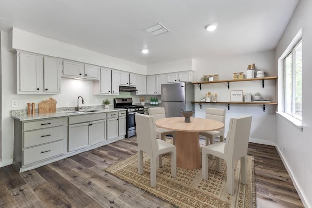 5912 Wagon Bnd, Austin, TX 78744 - kitchen featuring appliances with stainless steel finishes, dark wood-type flooring, under cabinet range hood, open shelves, and recessed lighting