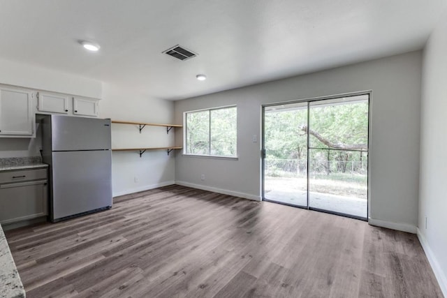 unfurnished living room featuring visible vents, baseboards, and wood finished floors