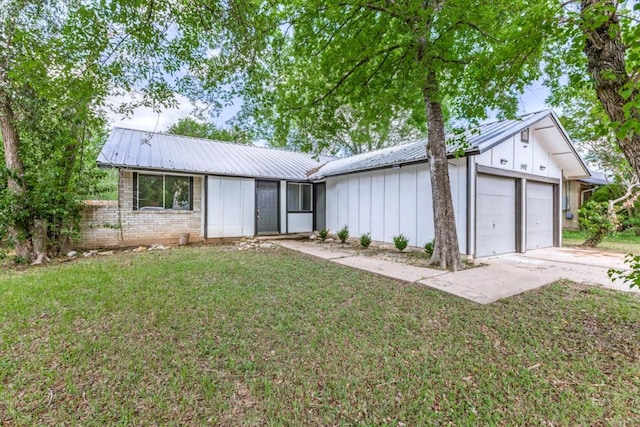 5912 Wagon Bnd, Austin, TX 78744 - view of front of property with board and batten siding, an attached garage, a metal roof, a front lawn, and concrete driveway