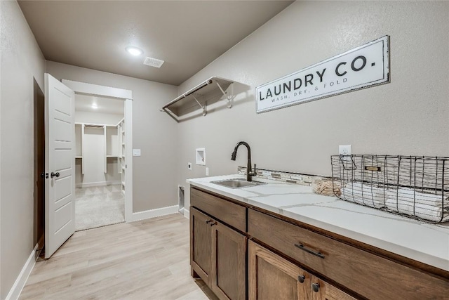 2502 Truman Dr, Lago Vista, TX 78645 - washroom with washer hookup, electric dryer hookup, a sink, baseboards, and light wood-style floors